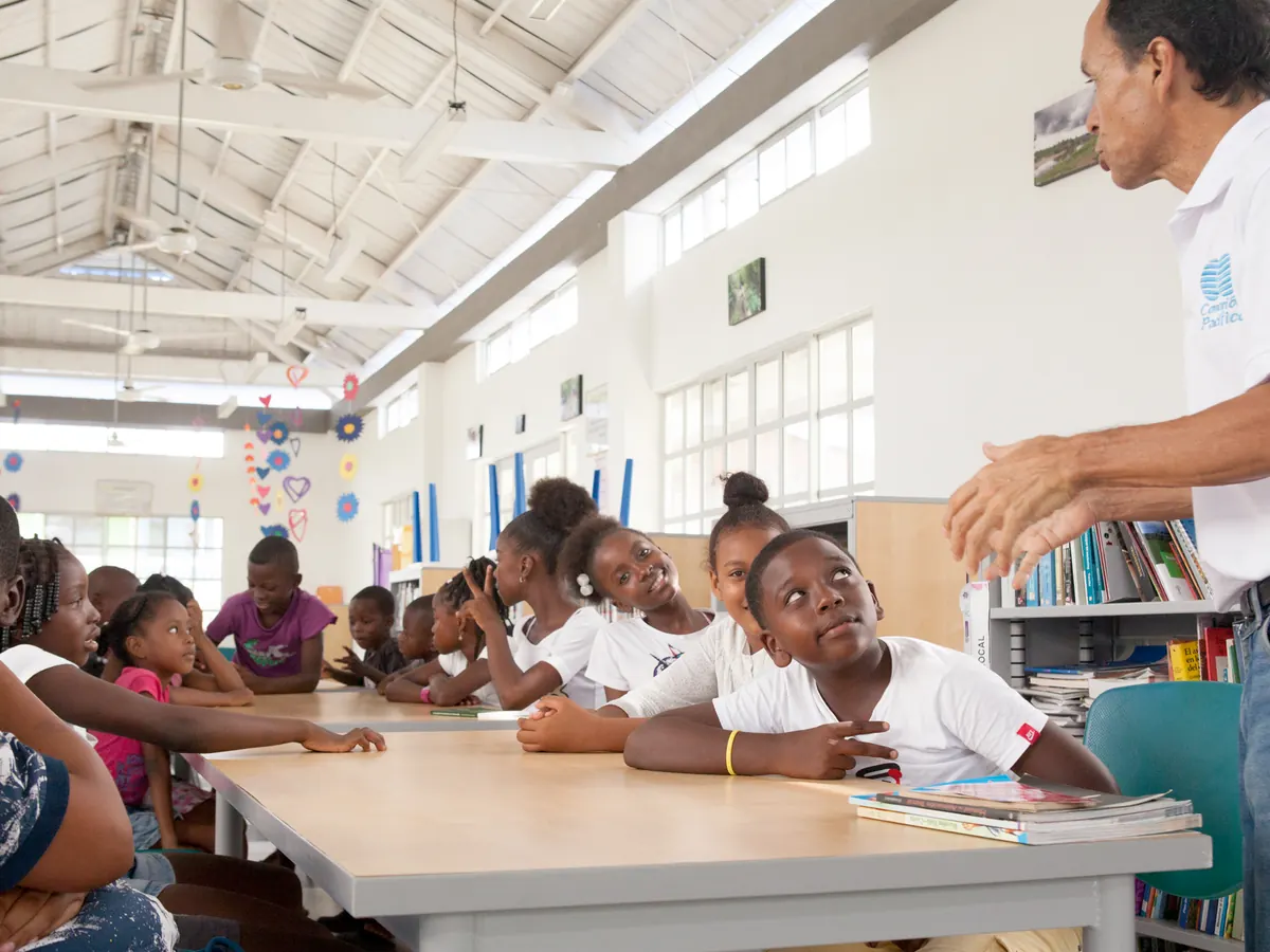 Facilitador conversando con estudiantes en una biblioteca