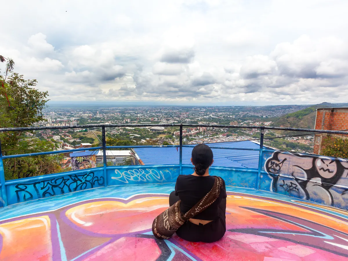 Mujer sentada en un mirador contemplando la ciudad de Cali