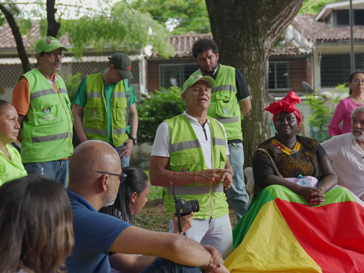 Reunión comunitaria al aire libre con líderes y vecinos sentados en círculo