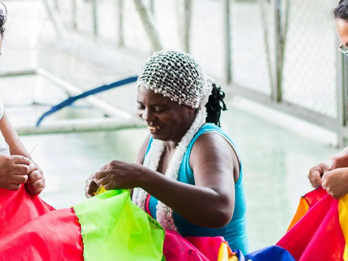 Mujeres sosteniendo juntas una colcha de tela de colores